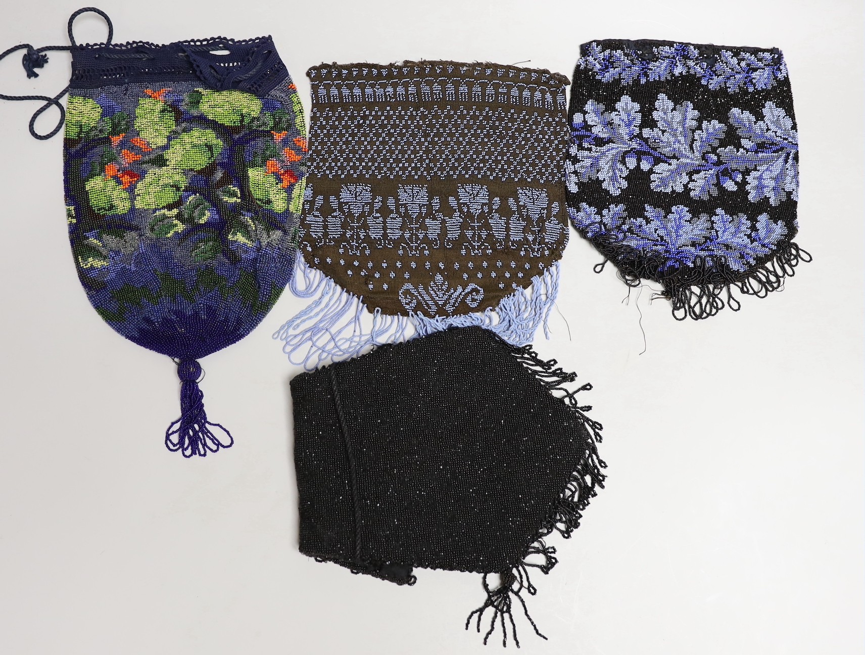 A mid 19th century finely knitted blue beaded bag, another similar later 19th century bag, a multicoloured floral bag with bead tassel to base and a 1930’s black beaded bag (4)